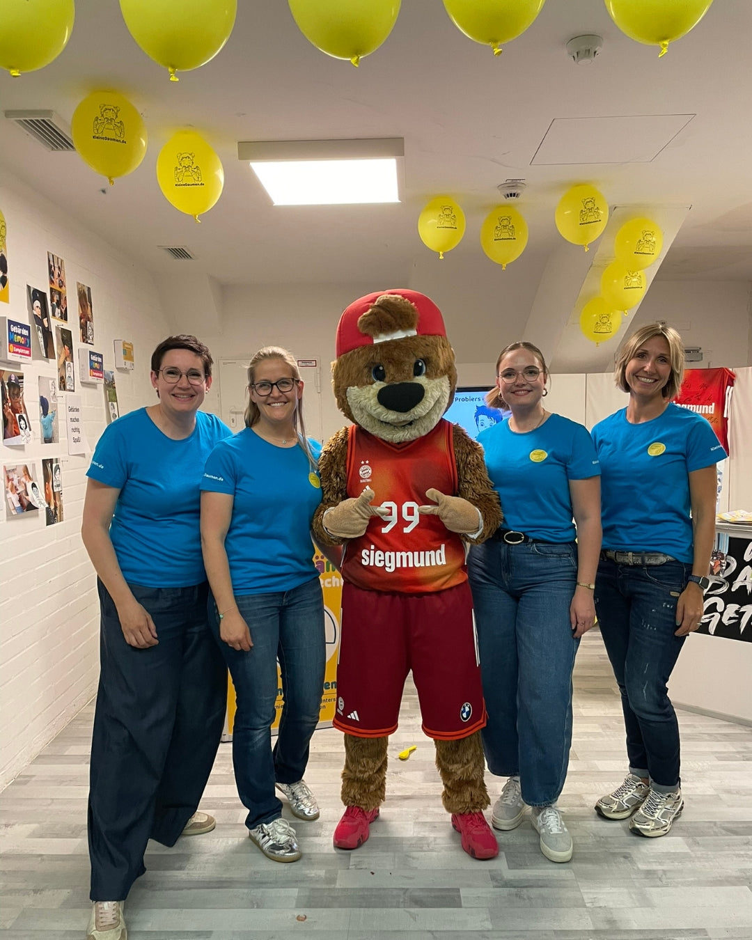 Helferinnen von KleineDaumen mit Ben, dem Maskottchen vom FC Bayern Basketball